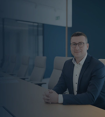 Der Steuerberater Herr Wittig an einem Konferenztisch im Büro, freundlich in die Kamera blickend
