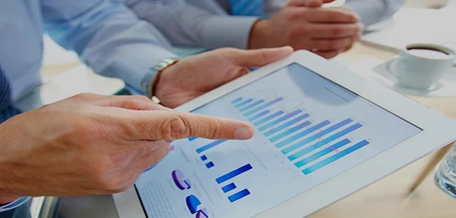Mann zeigt auf ein Balkendiagramm auf einem Tablet, das er in der Hand hält